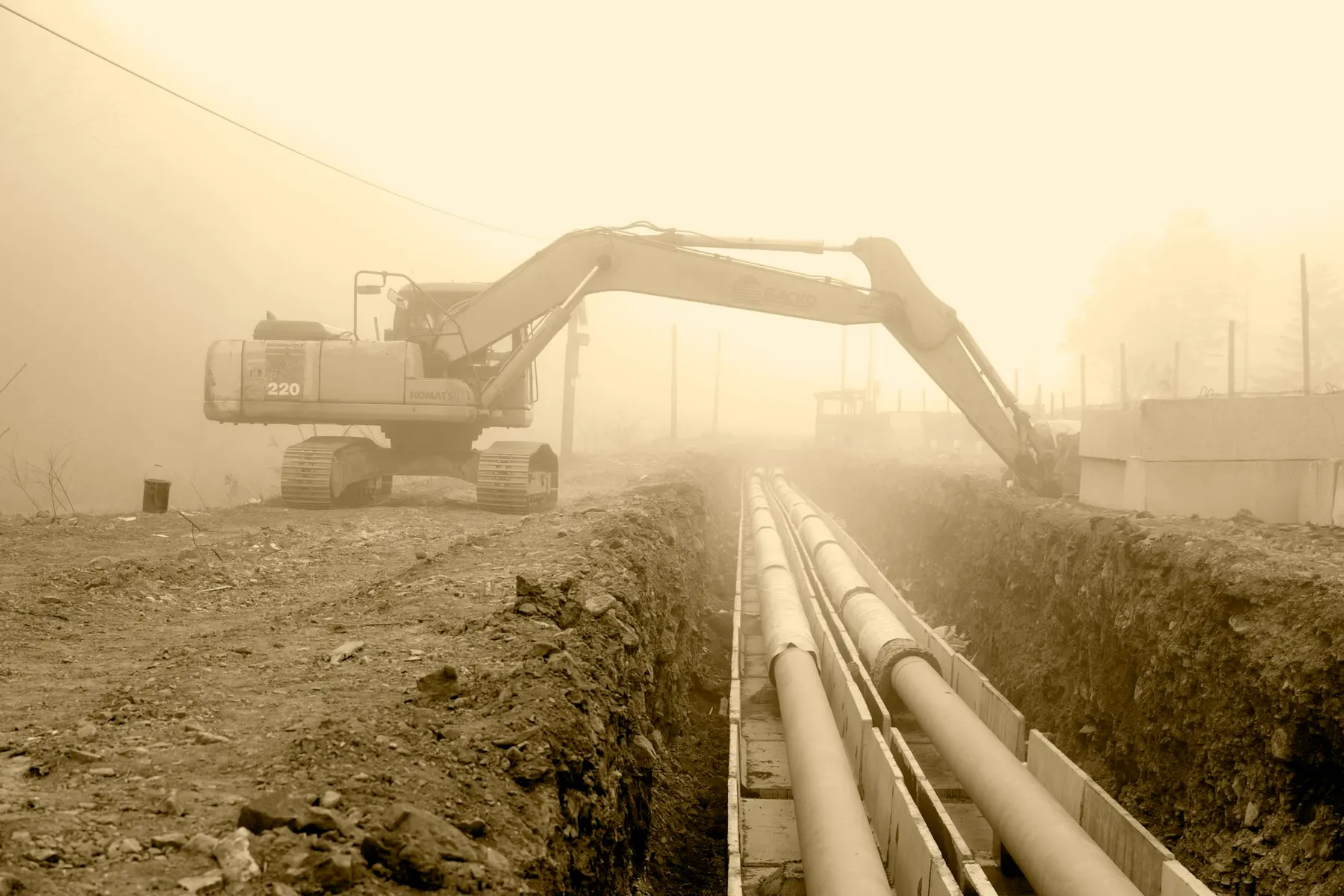 An excavator working beside a pipeline trench